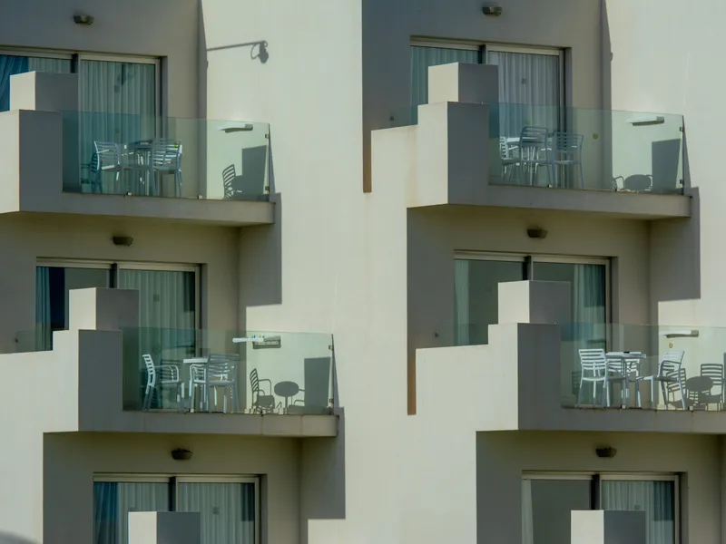 Cream-toned building facade with glass balconies and outdoor seating, Texas real estate