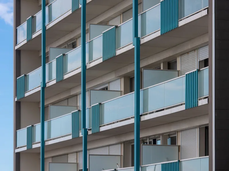 Building facade with teal-accented balconies and glass railings, Texas real estate